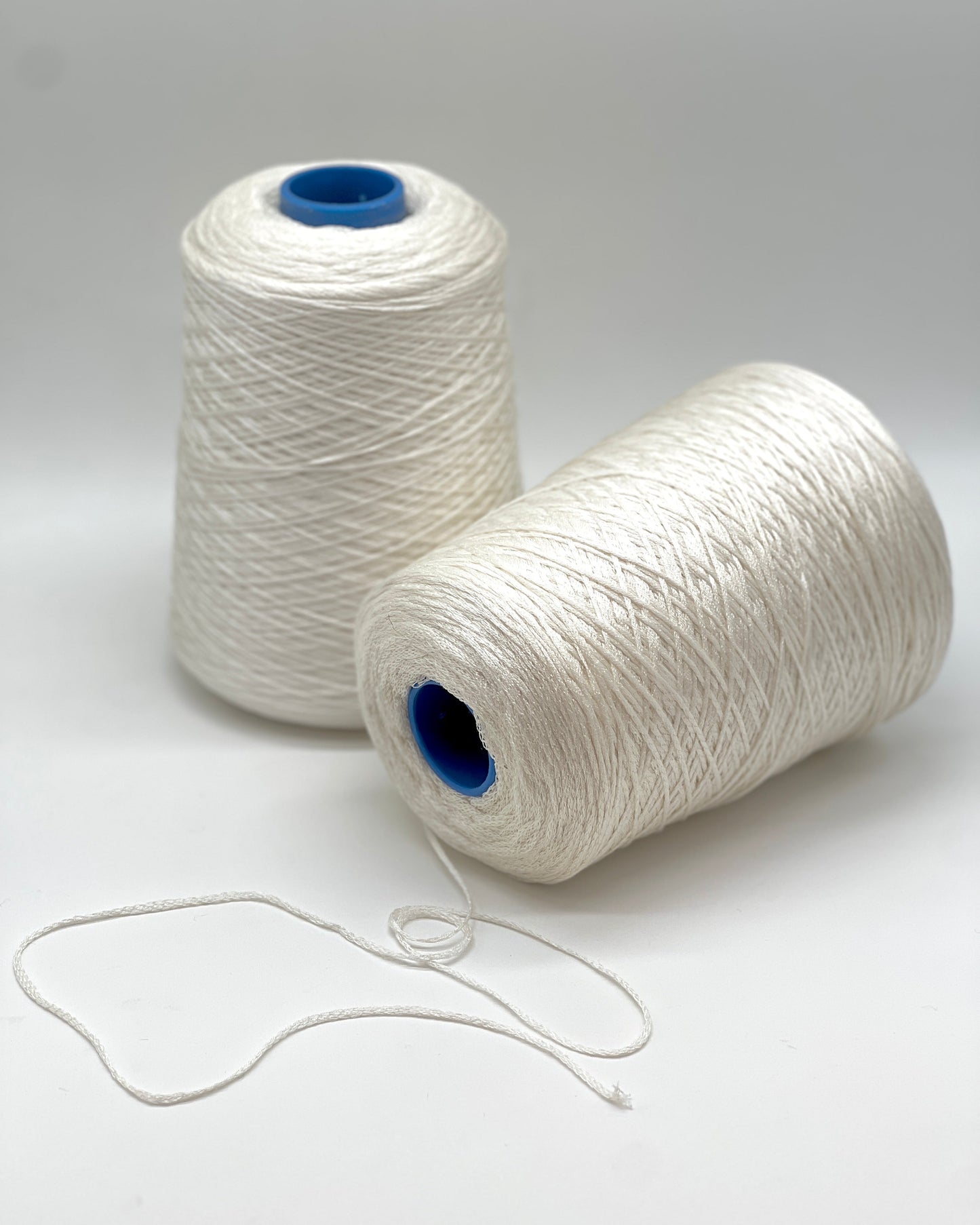 Luxury iDOKNiT fingering weight yarn, SETA SHAPPE by RiGo Italy. 100% Seta Shappe Silk featuring a sophisticated chainette structure for superior breathability and drape, 420m/100g. Authentic Italian-made silk on cones, color 2153 White, curated by iDOKNiT for elite hand and machine knitting projects.