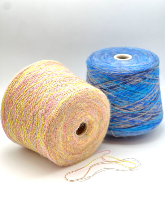 Two spools of yarn, one multicolored and one blue, on a white background.