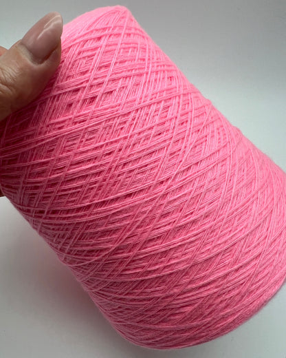 Pink yarn ball held by a hand on a light gray background