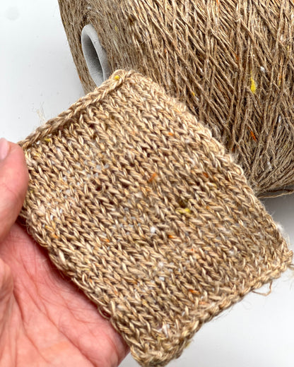 Close-up of a hand holding a piece of textured brown fabric against a white background
