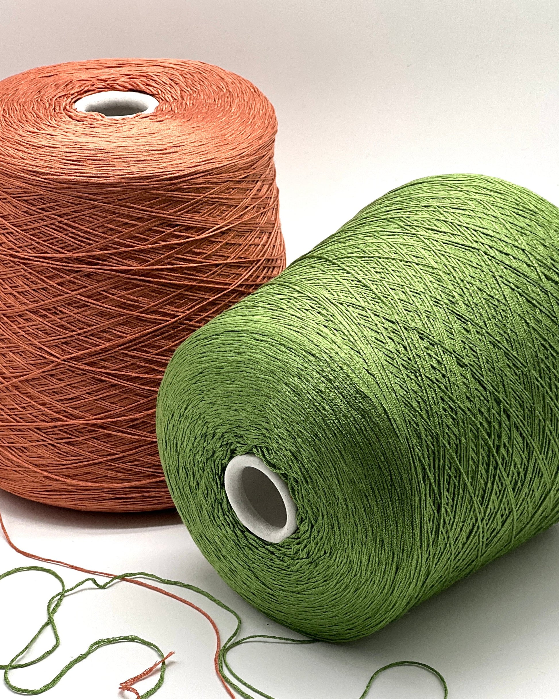 Two spools of yarn, one brown and one green, on a white background.