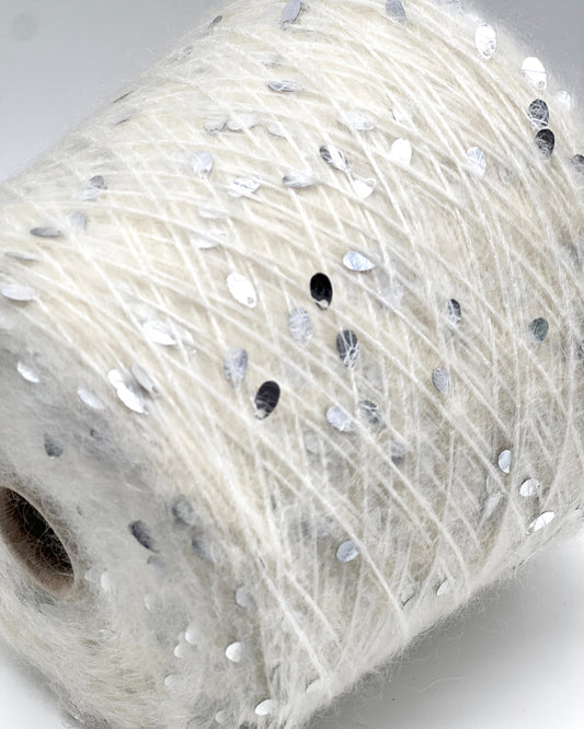 Spool of white yarn with small stones on a light gray background