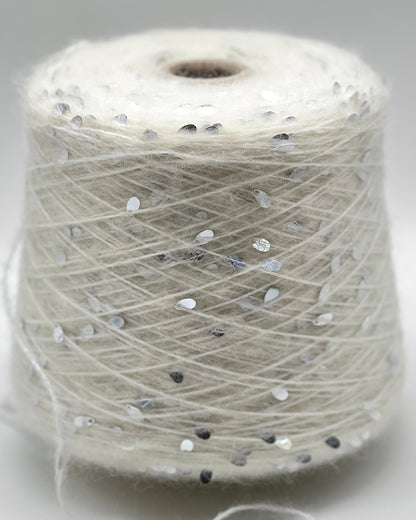 Spool of white thread with small black and gray dots on a light gray background