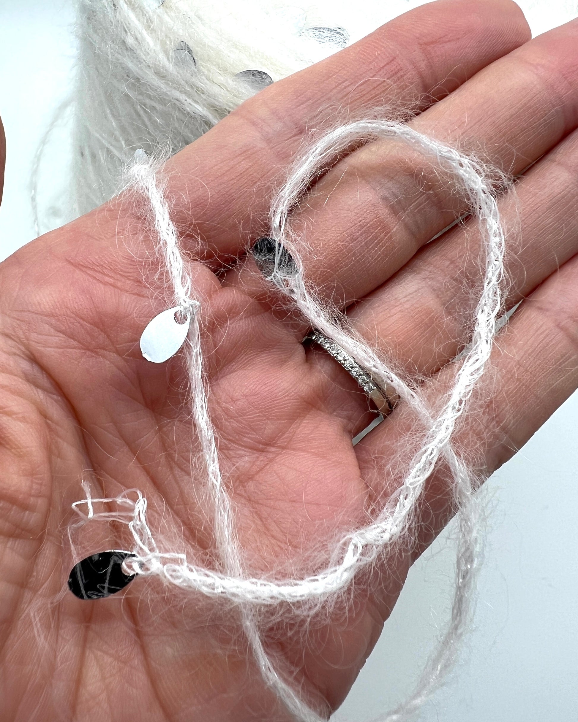 Hand holding a small heart-shaped object with white string