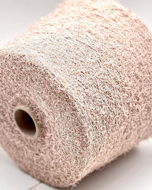 Close-up of a roll of beige knitted fabric on a light background