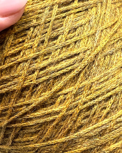 Close-up of a ball of yellow yarn with a hand for scale.