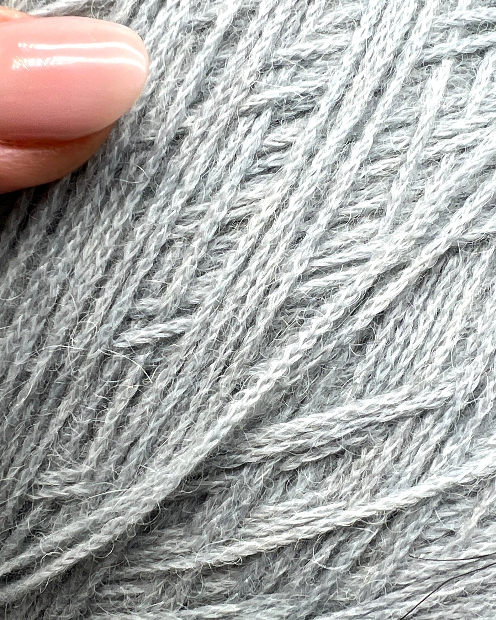 Close-up of gray yarn with a hand holding it