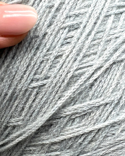 Close-up of gray yarn with a hand holding it