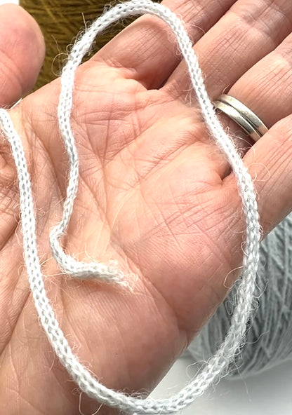 White string held in a hand with a blurred background