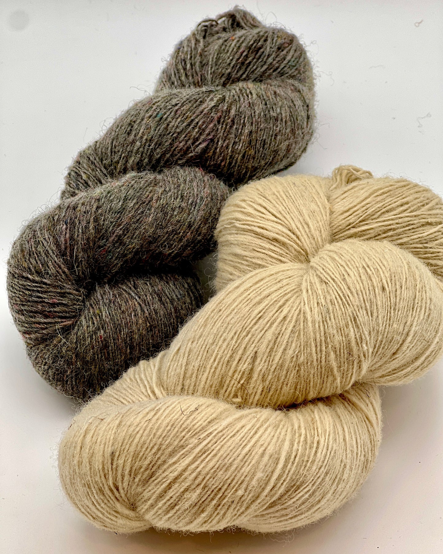 DUNDAGA 6.1 rustic Latvian wool yarn by Paces Vilnas Fabrika, single-ply fingering weight with high natural lanolin content, hand-dyed skeins in natural beige and grey tweed, traditional non-superwash heritage wool, photographed for iDOKNiT yarn shop.