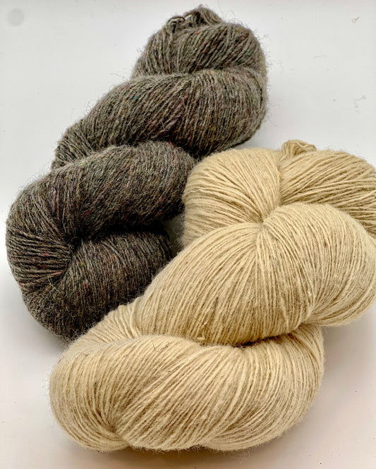 DUNDAGA 6.1 rustic Latvian wool yarn by Paces Vilnas Fabrika, single-ply fingering weight with high natural lanolin content, hand-dyed skeins in natural beige and grey tweed, traditional non-superwash heritage wool, photographed for iDOKNiT yarn shop.