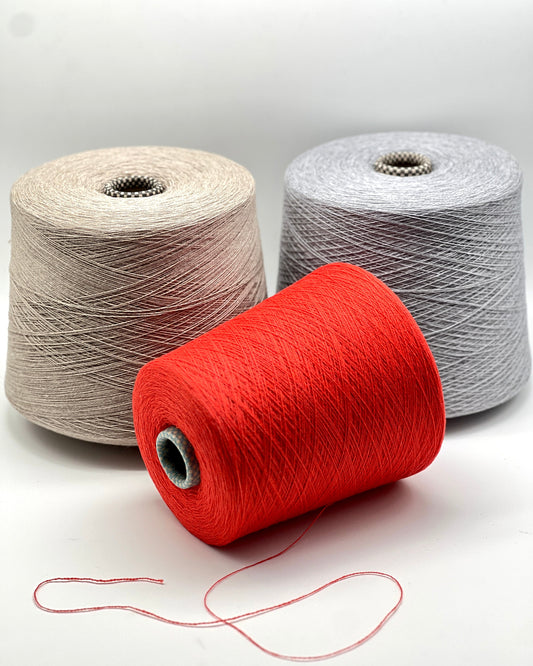 Three spools of yarn in red, beige, and gray on a white background
