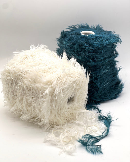 Two skeins of yarn, one white and one blue, on a light gray background.