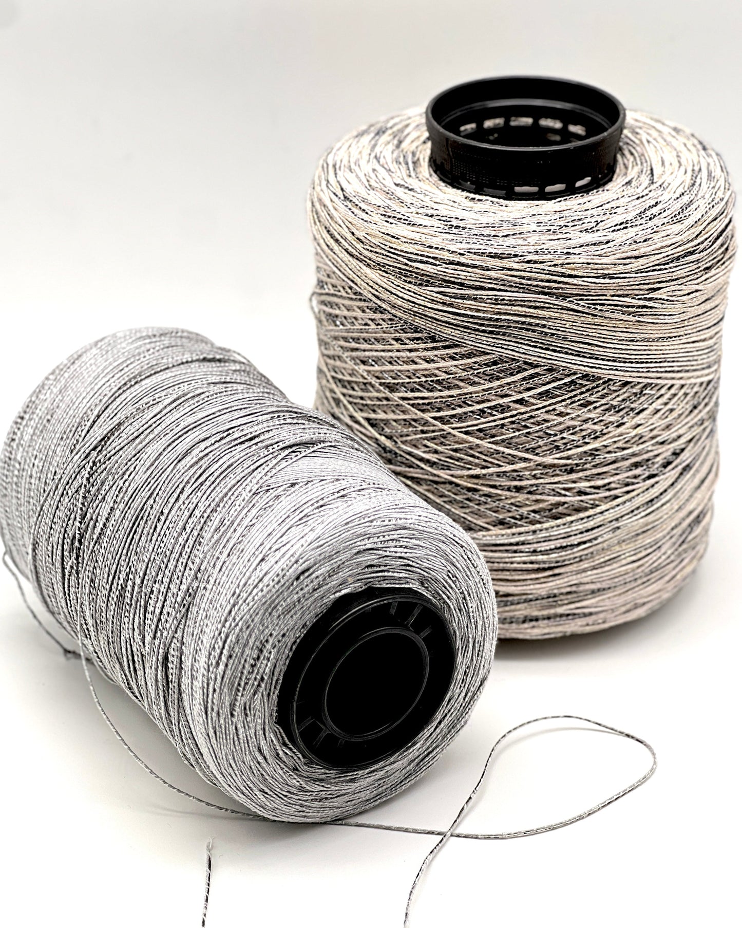 Two spools of gray thread on a white background