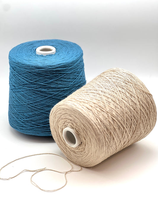 Two spools of yarn, one blue and one beige, on a white background.