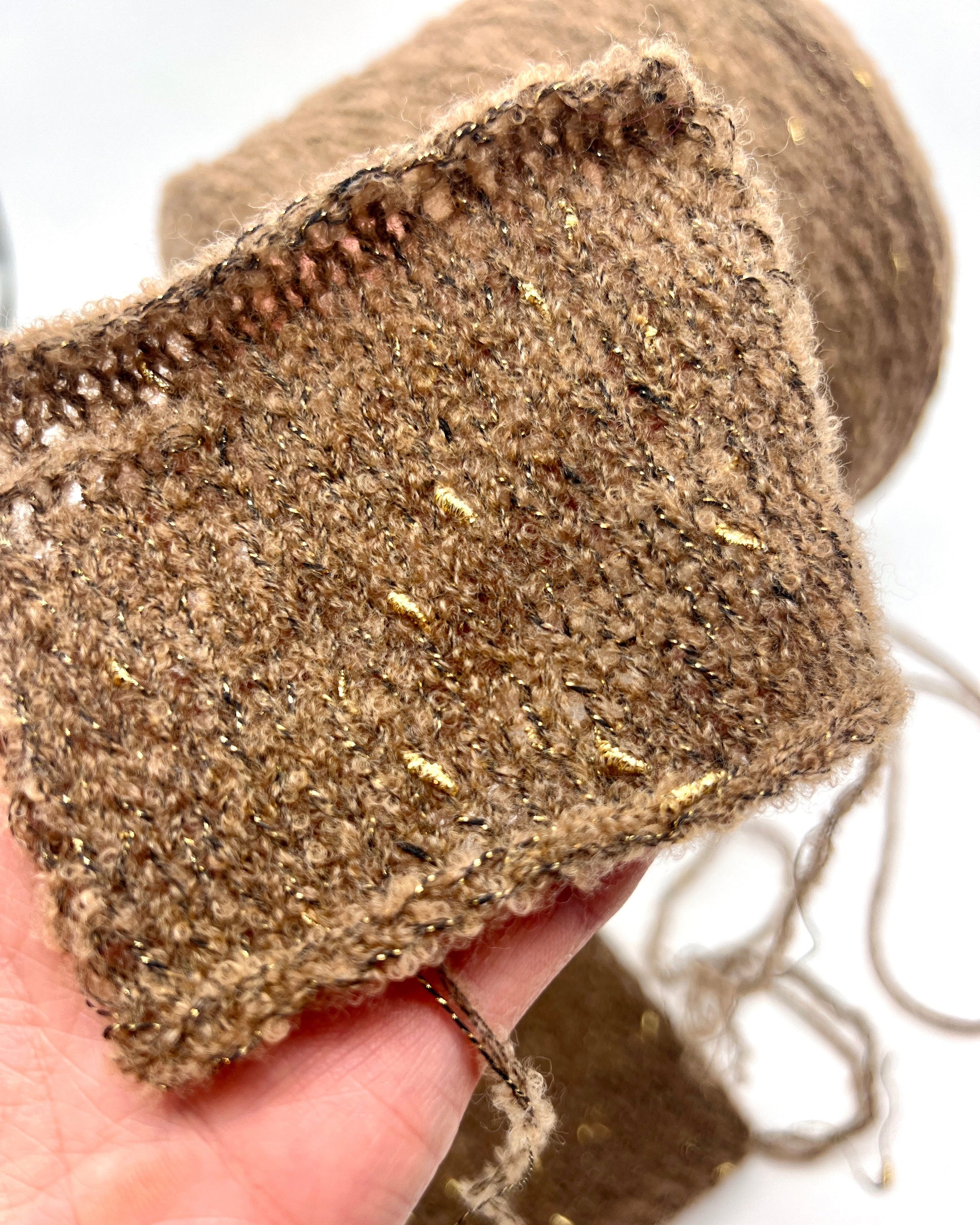 Close-up of a textured brown fabric strip held by a hand on a white background