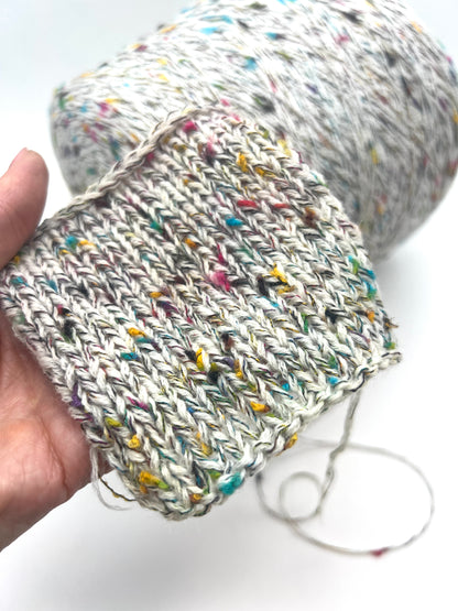 Multicolored yarn ball held by a hand on a white background