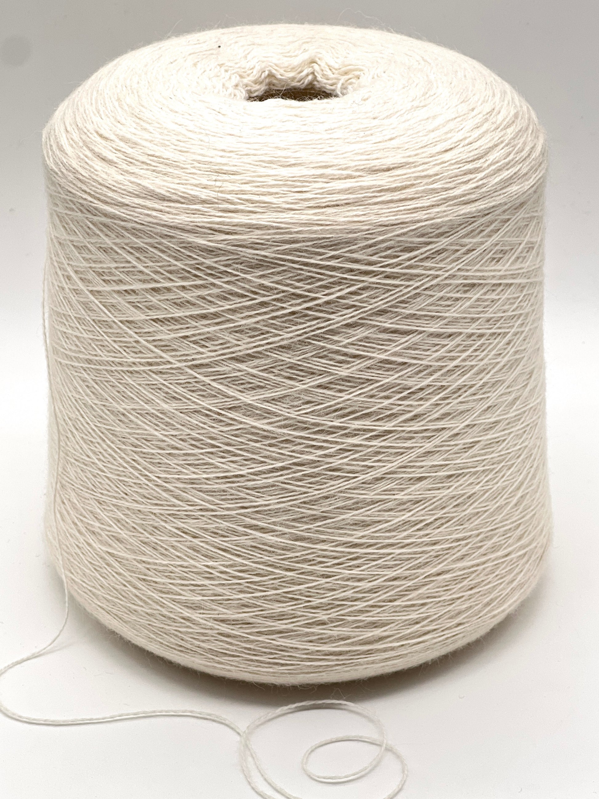 Spool of white yarn on a light gray background