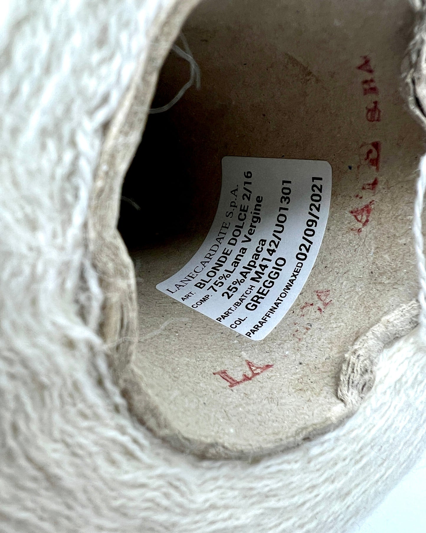 Close-up of a yarn ball with a label inside, showing brand and product details.