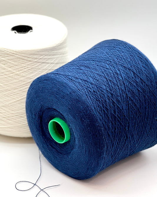 Blue spool of yarn with a green core on a white background