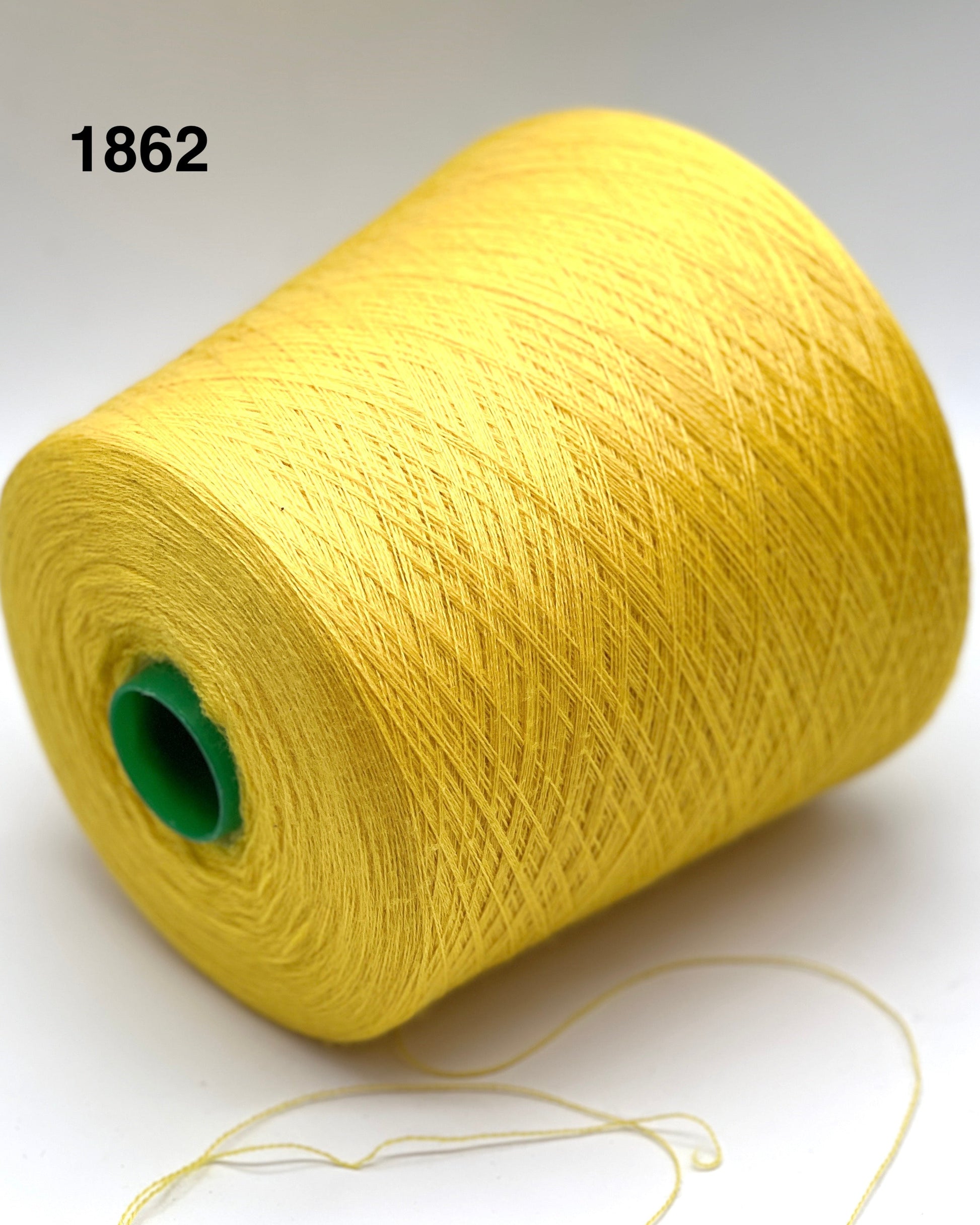 Yellow spool of yarn with a green core on a white background
