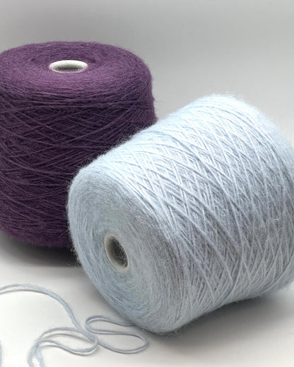 Two balls of yarn, one purple and one white, on a light gray background.