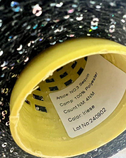 Close-up of a label on a black sequin fabric with a yellow border.