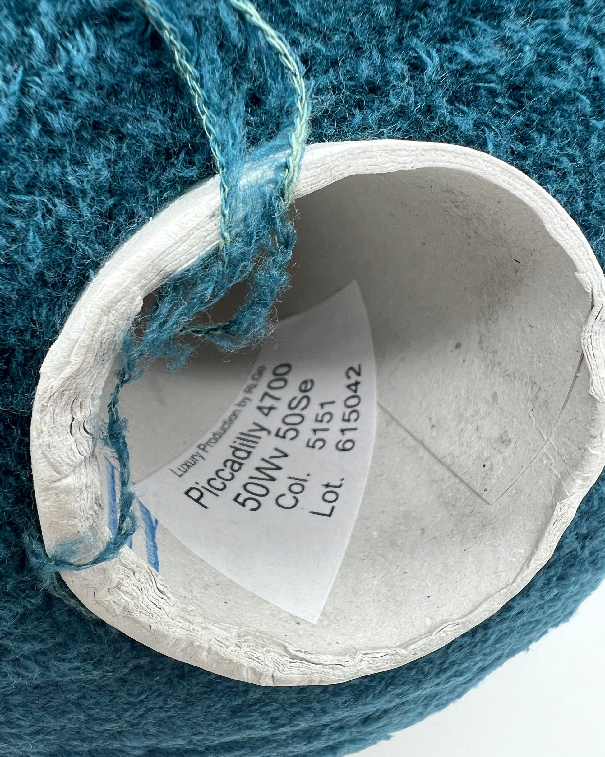 Close-up of a spool of blue yarn with a label on a textured blue background