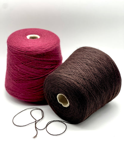 Two spools of yarn, one pink and one brown, on a white background.