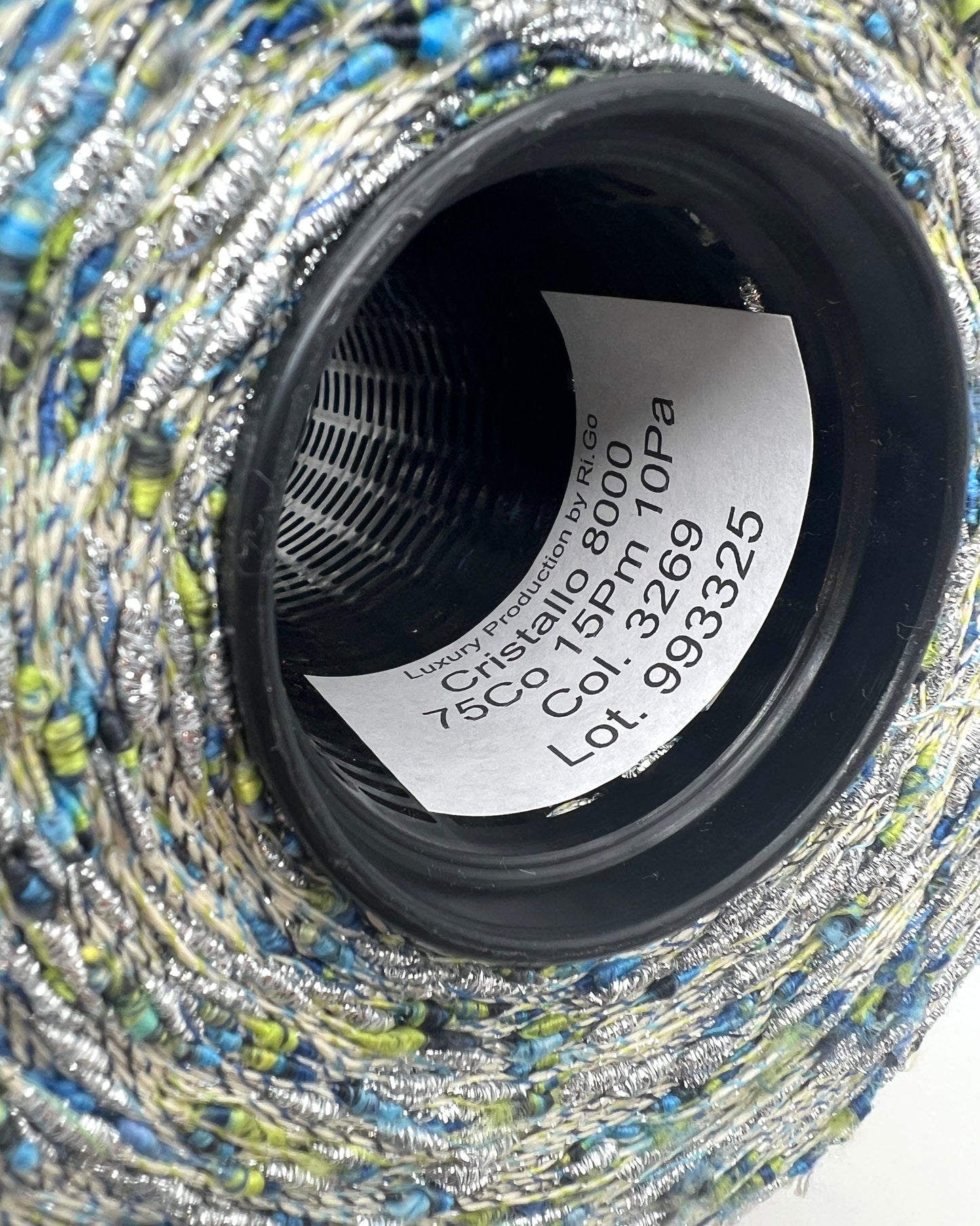 Close-up of a spool of thread with label inside, showing brand and product details.
