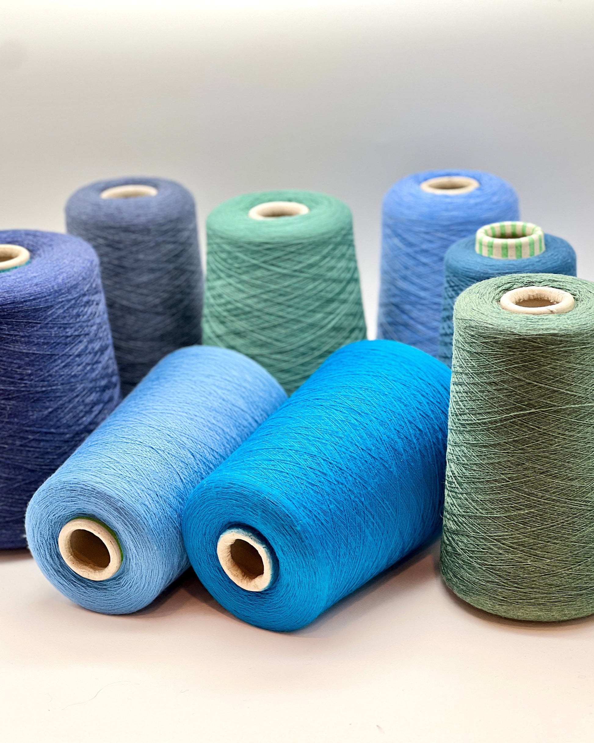 Spools of blue and green yarn on a light background