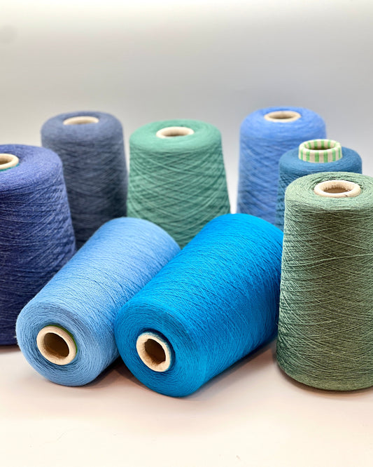 Spools of blue and green yarn on a light background