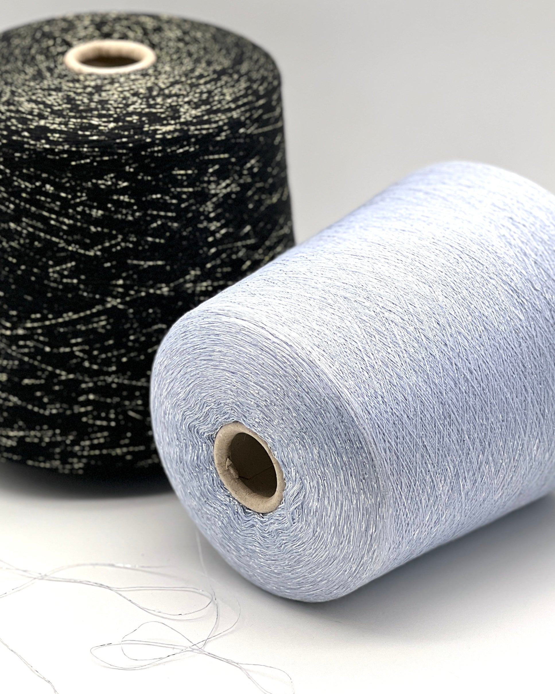 A luxurious cone of Pecci Filati SHIMMER yarn, a modern 50% Cotton, 25% Linen, 14% Polyester, and 12% Polyamide (Lurex) blend. The image showcases the refined metallic glow and delicate texture of this 3400m/100g Italian extrafine yarn, ideal for high-end blending. Authentic luxury fiber available at iDOKNiT.com.