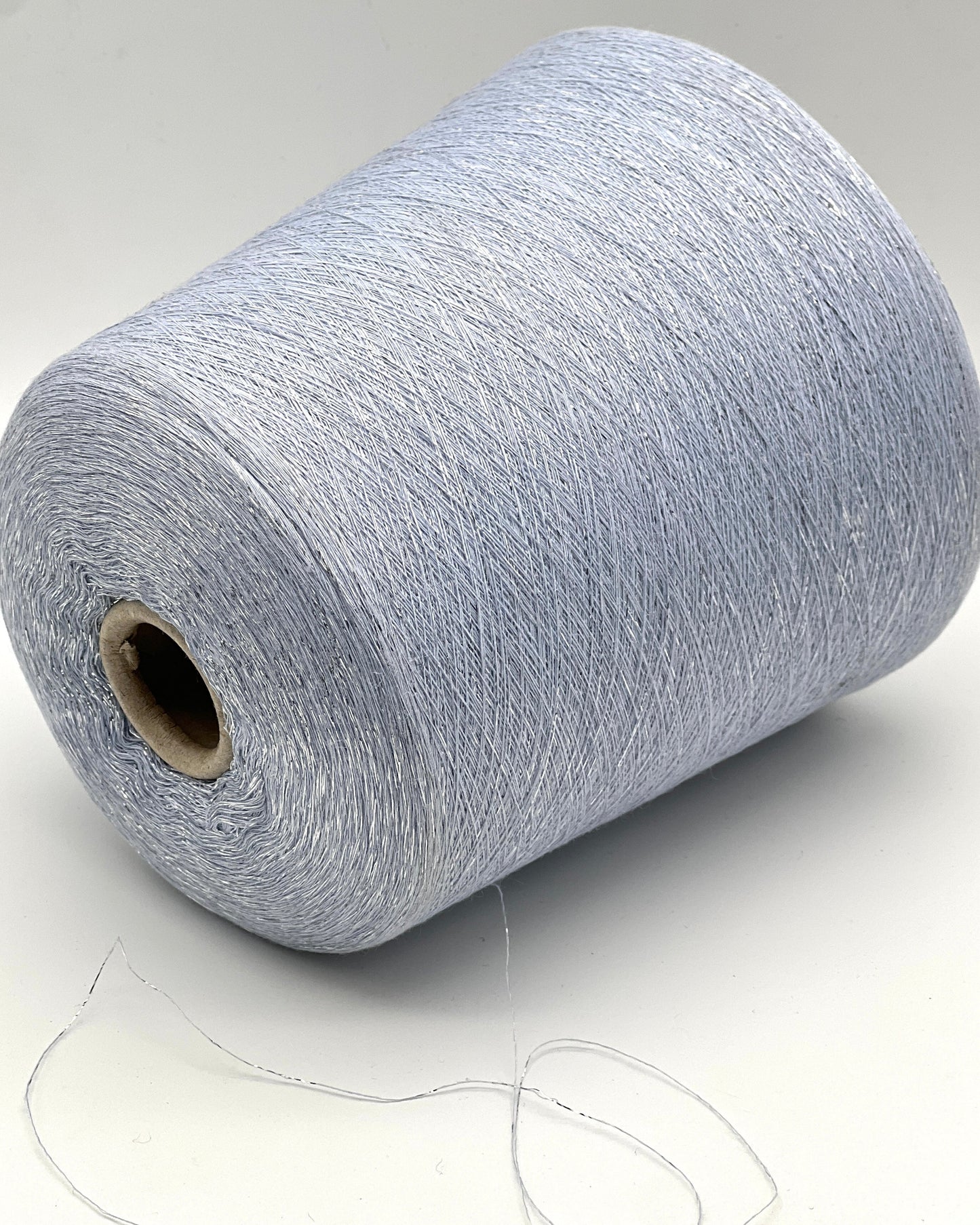 A luxurious cone of Pecci Filati SHIMMER yarn, a modern 50% Cotton, 25% Linen, 14% Polyester, and 12% Polyamide (Lurex) blend. The image showcases the refined metallic glow and delicate texture of this 3400m/100g Italian extrafine yarn, ideal for high-end blending. Authentic luxury fiber available at iDOKNiT.com.