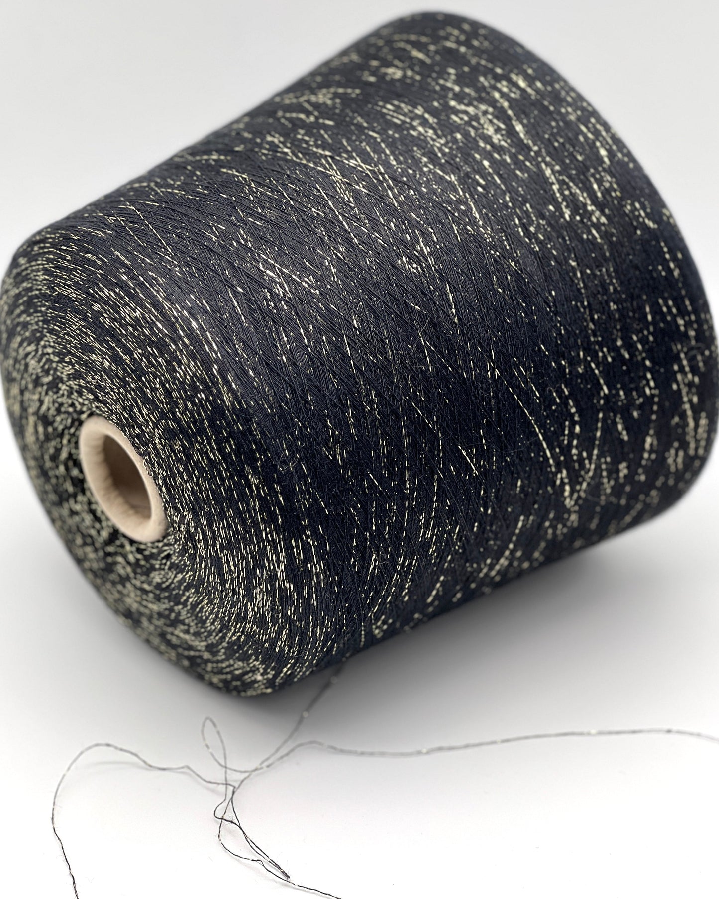 A luxurious cone of Pecci Filati SHIMMER yarn, a modern 50% Cotton, 25% Linen, 14% Polyester, and 12% Polyamide (Lurex) blend. The image showcases the refined metallic glow and delicate texture of this 3400m/100g Italian extrafine yarn, ideal for high-end blending. Authentic luxury fiber available at iDOKNiT.com.