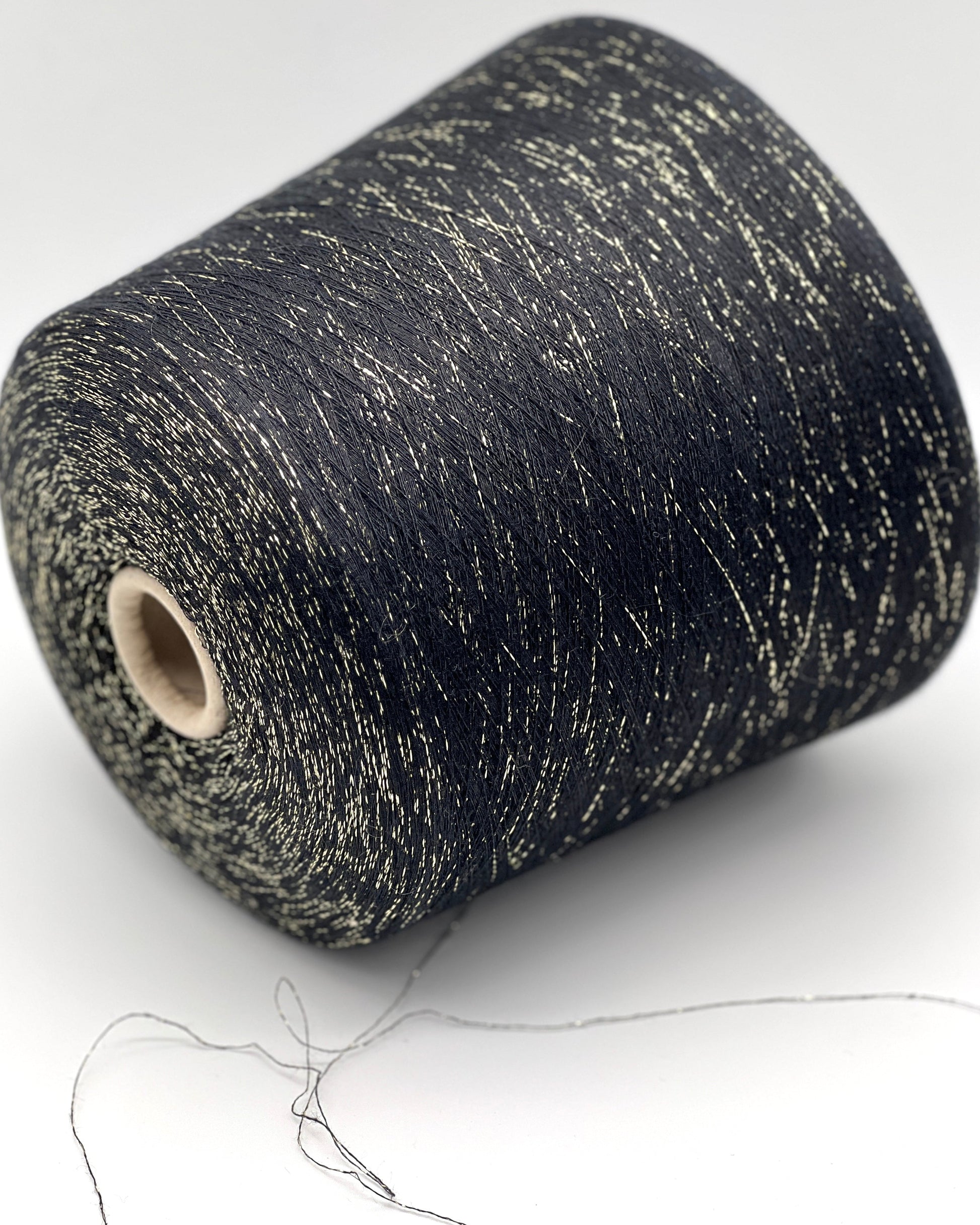 A luxurious cone of Pecci Filati SHIMMER yarn, a modern 50% Cotton, 25% Linen, 14% Polyester, and 12% Polyamide (Lurex) blend. The image showcases the refined metallic glow and delicate texture of this 3400m/100g Italian extrafine yarn, ideal for high-end blending. Authentic luxury fiber available at iDOKNiT.com.