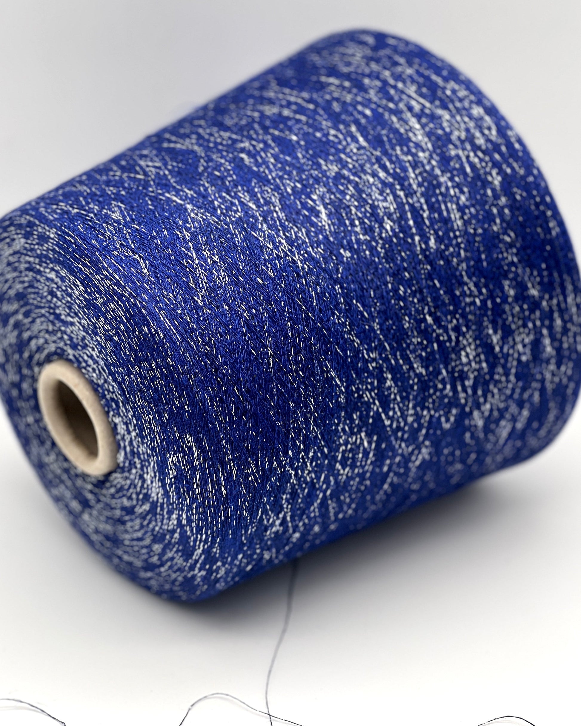 A luxurious cone of Pecci Filati SHIMMER yarn, a modern 50% Cotton, 25% Linen, 14% Polyester, and 12% Polyamide (Lurex) blend. The image showcases the refined metallic glow and delicate texture of this 3400m/100g Italian extrafine yarn, ideal for high-end blending. Authentic luxury fiber available at iDOKNiT.com.