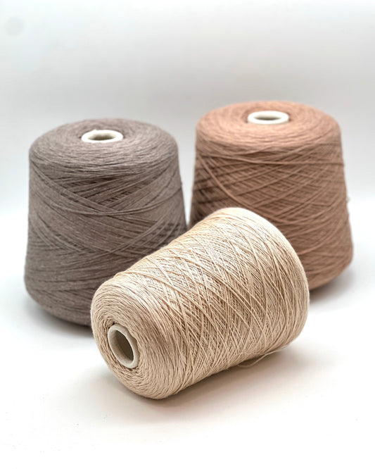 Three spools of beige and brown yarn on a white background