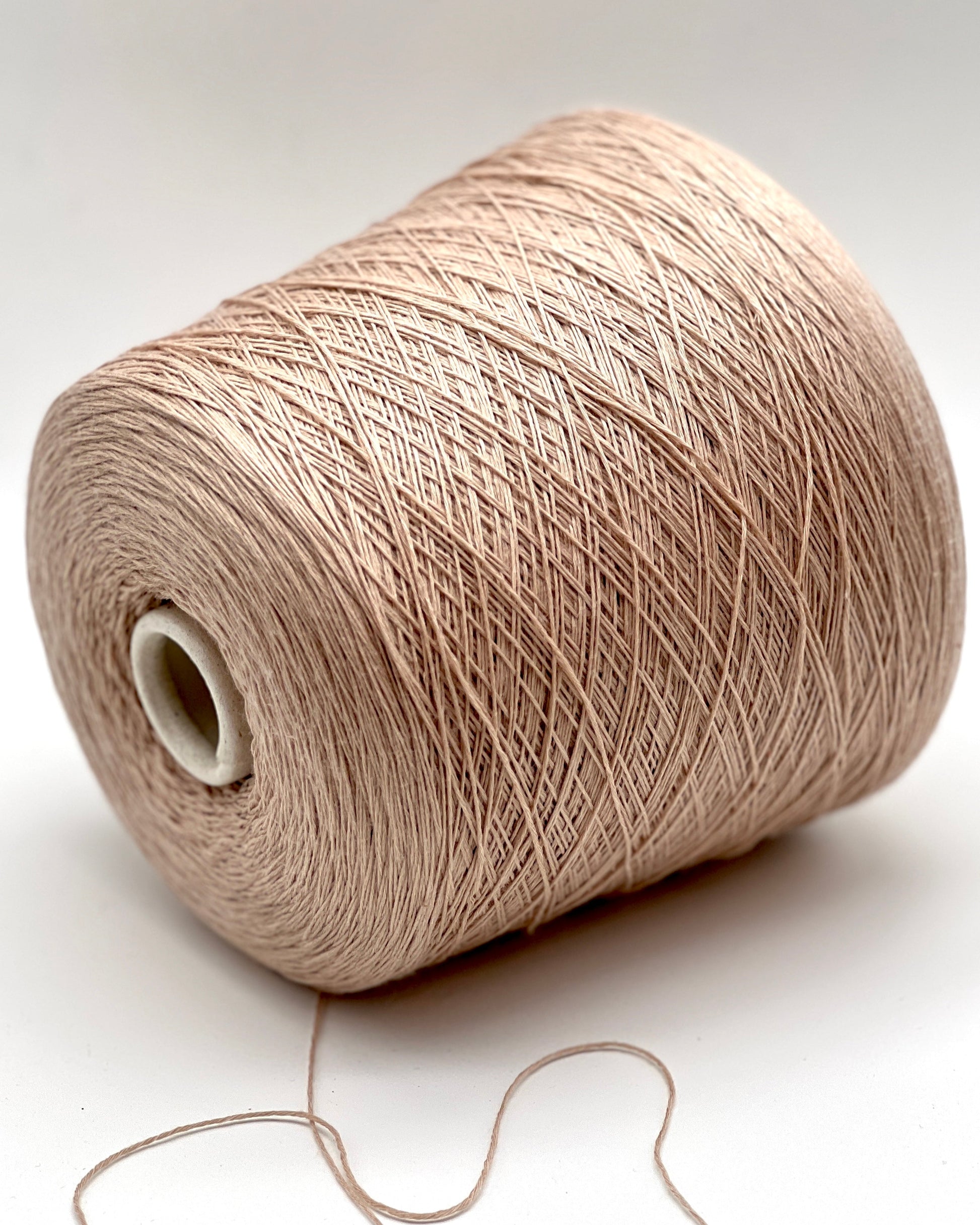 Spool of beige yarn on a white background