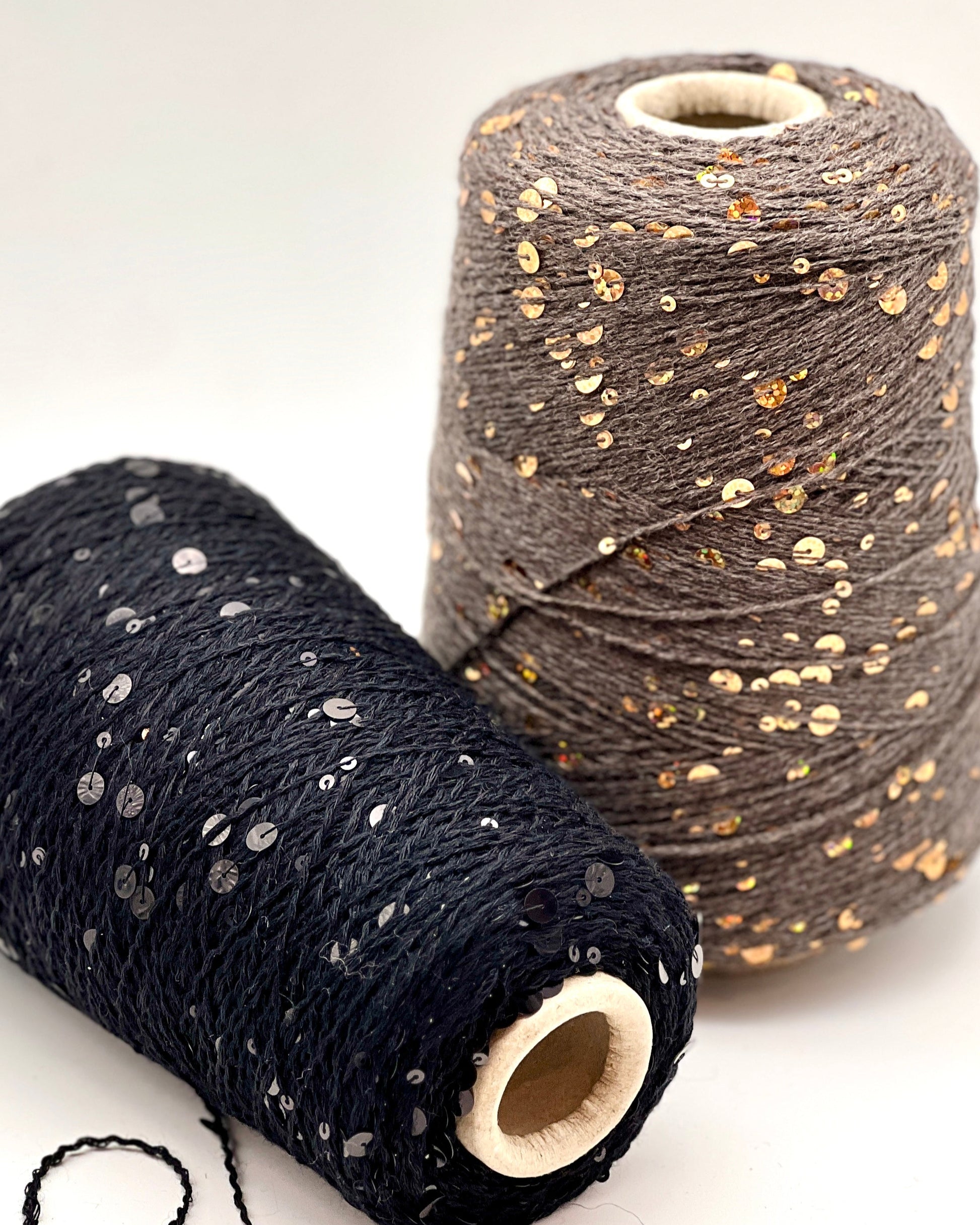 Two spools of yarn with sequin embellishments on a white background