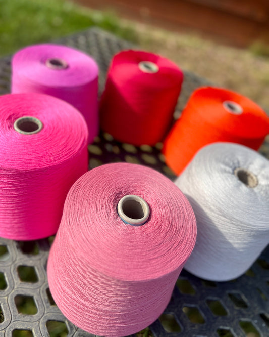 Colorful spools of thread on a metal surface with a blurred natural background