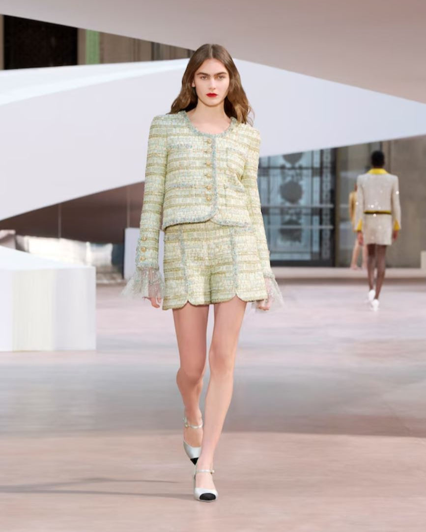 Model wearing a light green outfit on a runway
