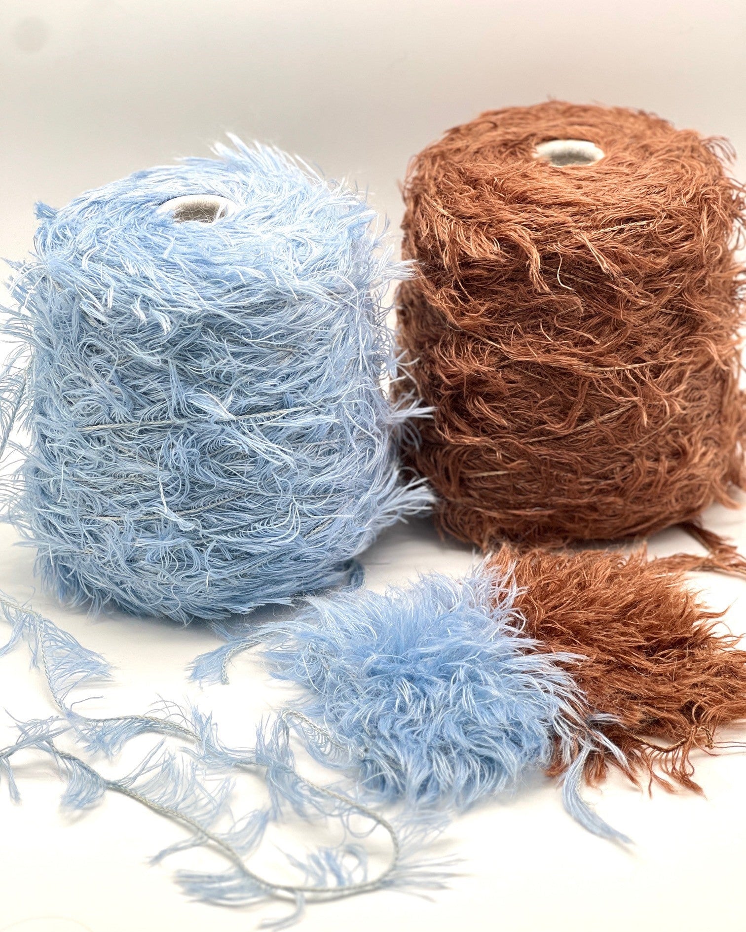 Two balls of yarn, one blue and one brown, on a white background.