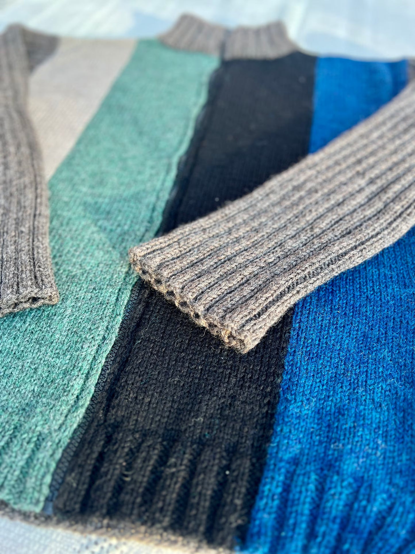 Close-up of a stack of colorful sweaters with a focus on the ribbed texture.