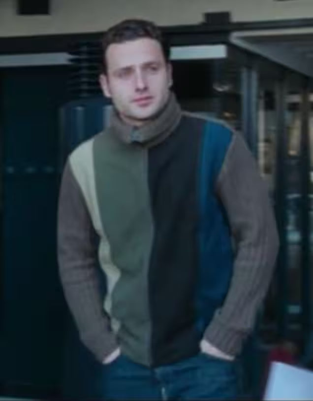 Man wearing a patterned sweater with a blurred indoor background