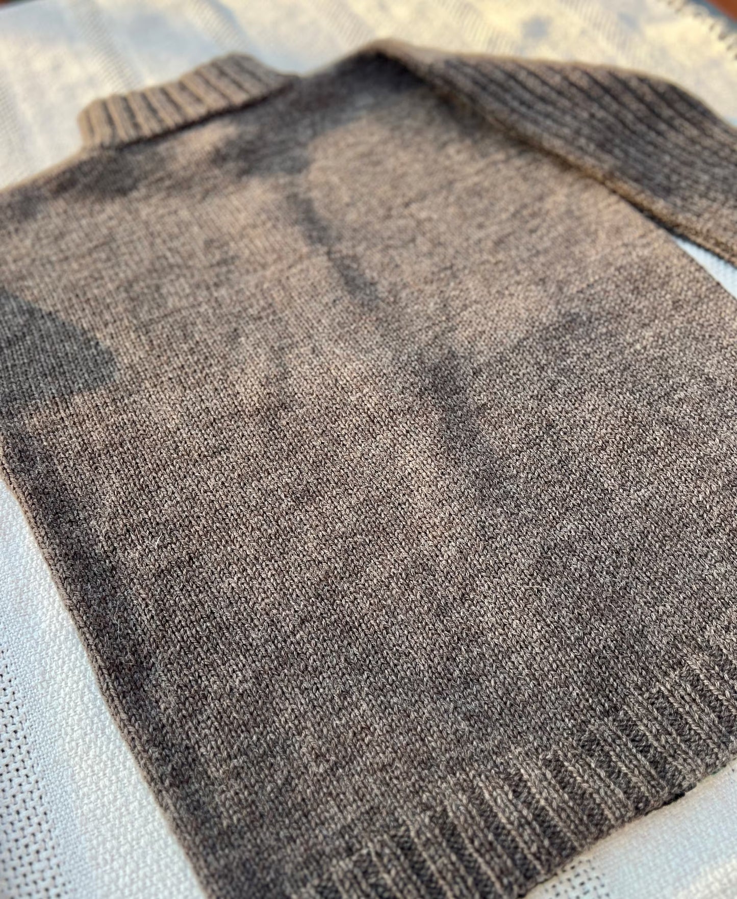 Close-up of a brown knitted sweater on a textured surface