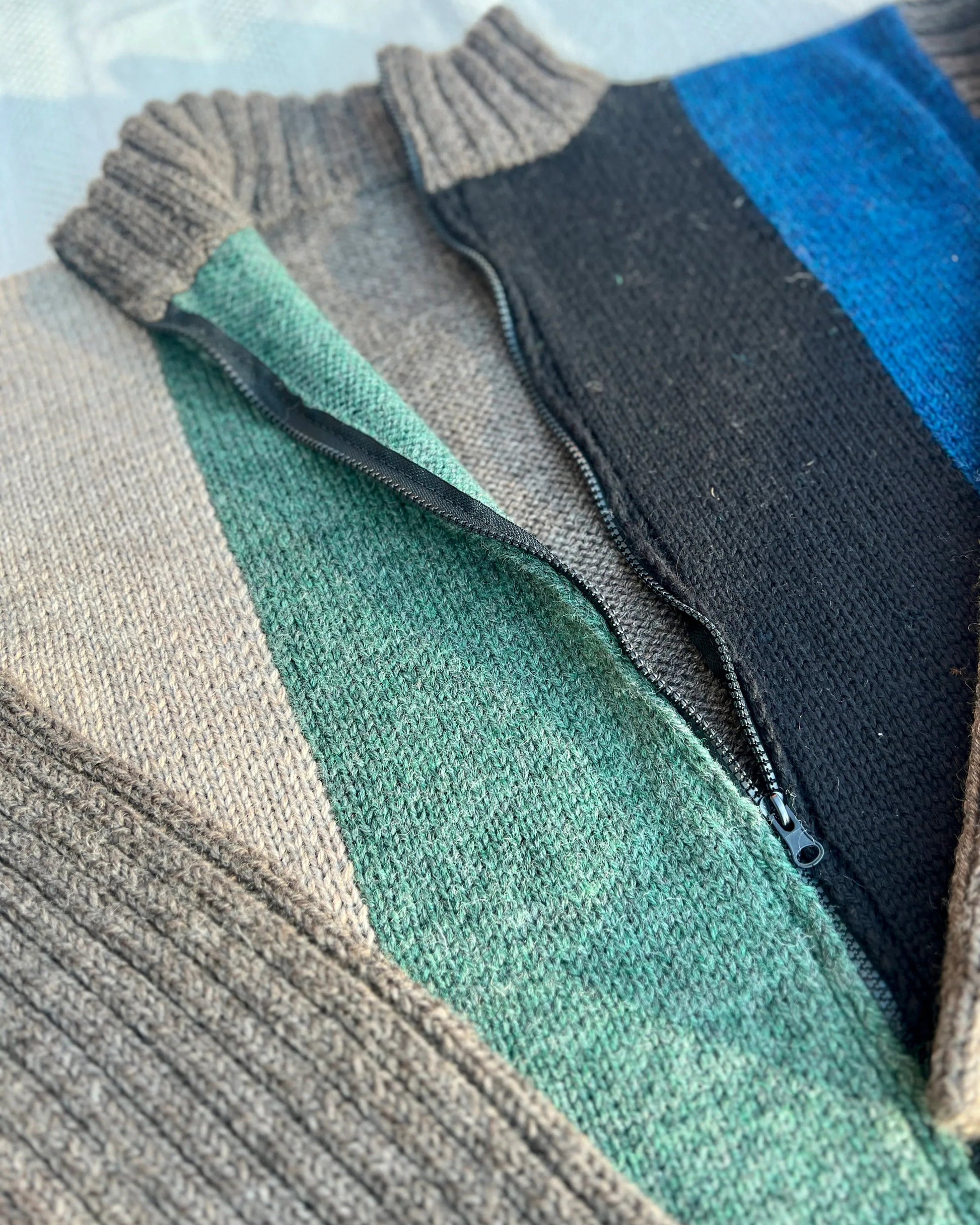 Close-up of a textured fabric with a gradient pattern in brown, green, black, and blue.