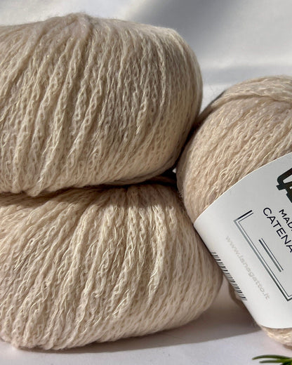 Three skeins of beige yarn with a label on a light background
