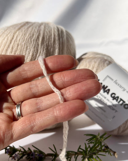 Hand holding a ball of yarn with a brand label in the background