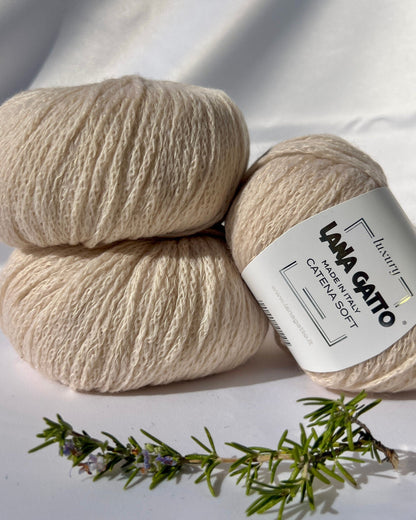 Two skeins of beige yarn with a Lana Gatto label on a white background with a sprig of lavender.